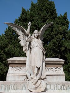 ein großes Familiengrab mit einer Engelsstatue darauf, der Engel hebt seine recht Hand zum Himmel zeigend